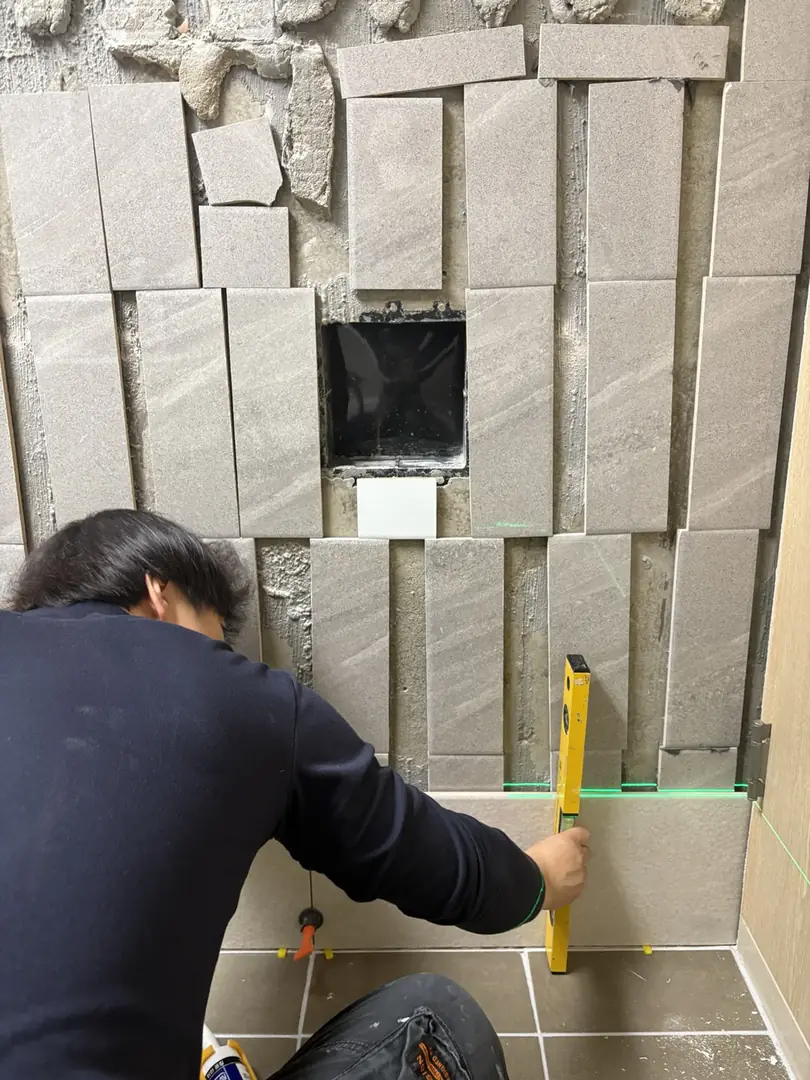 벽타일들뜸 보수 중 수평을 확인하며 벽에 타일을 다시 붙이는 작업